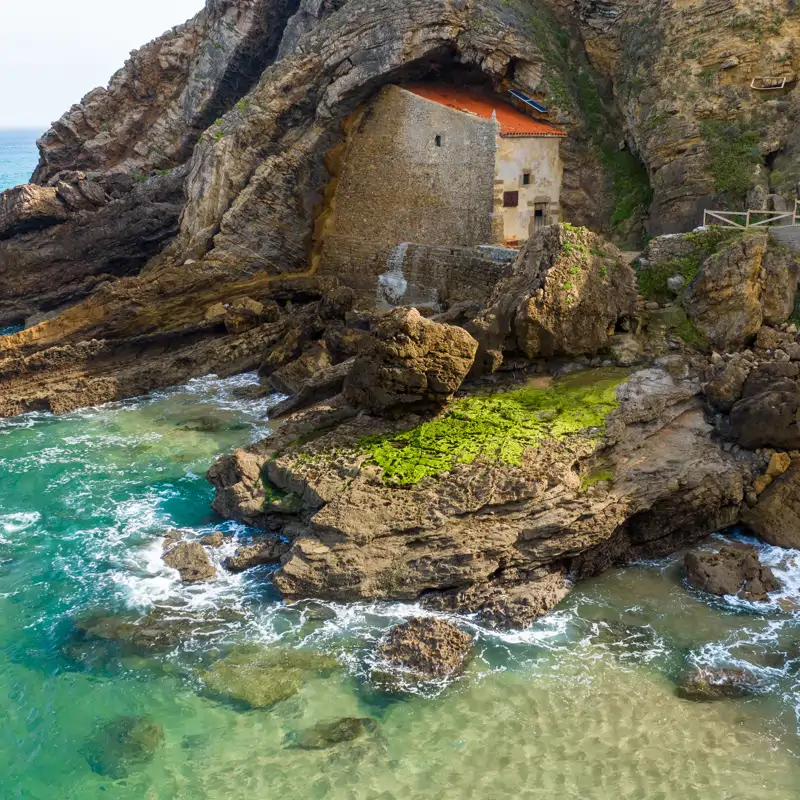 La playa de Cantabria con una ermita pegada en unos acantilados “tallados por un hachazo divino”